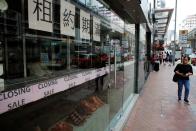 A woman walks past a shop with a closing sale in Hong Kong