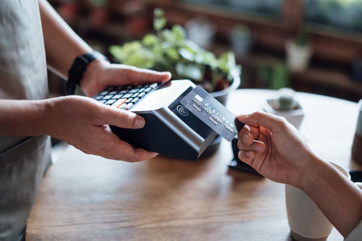 Close up of a woman's hand paying bill with credit card in a cafe, scanning on a card machine. Electronic payment. Banking and technology