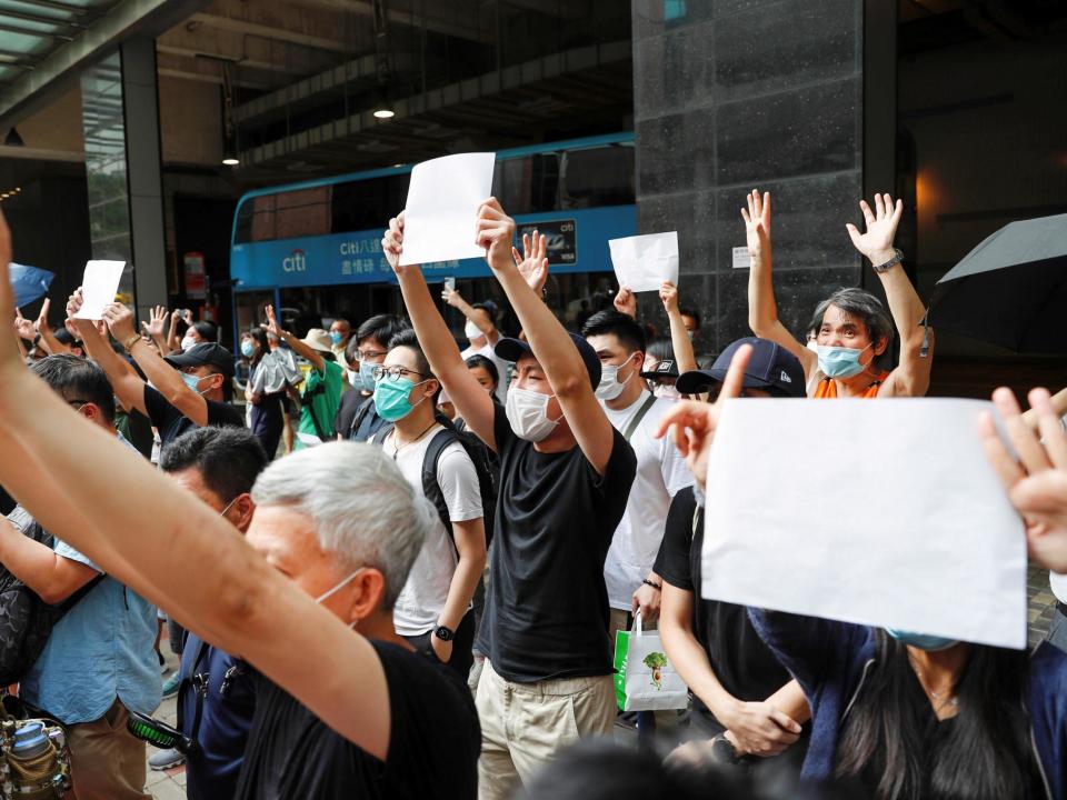 Supporters of an arrested anti-law protester raise white paper to avoid slogans banned under the national security law: Reuters