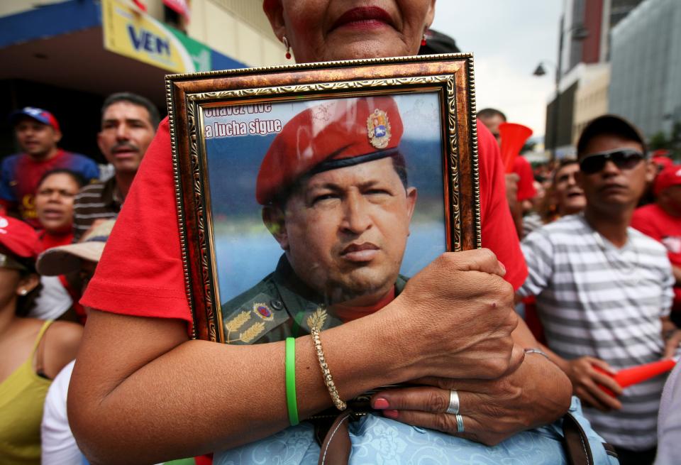 FILE - In this April 19, 2013 file photo, a supporter of Venezuela's newly sworn-in President Nicolas Maduro holds a picture of late President Hugo Chavez during Maduro's inauguration in Caracas, Venezuela. Civil rights and liberties around the world declined for the eighth straight year, dragged down by the Egyptian military's coup, Venezuela clinging to authoritarianism and Russia's crackdown on opposition groups, according to a pro-democracy watchdog group. (AP Photo/Gil Montano, File)