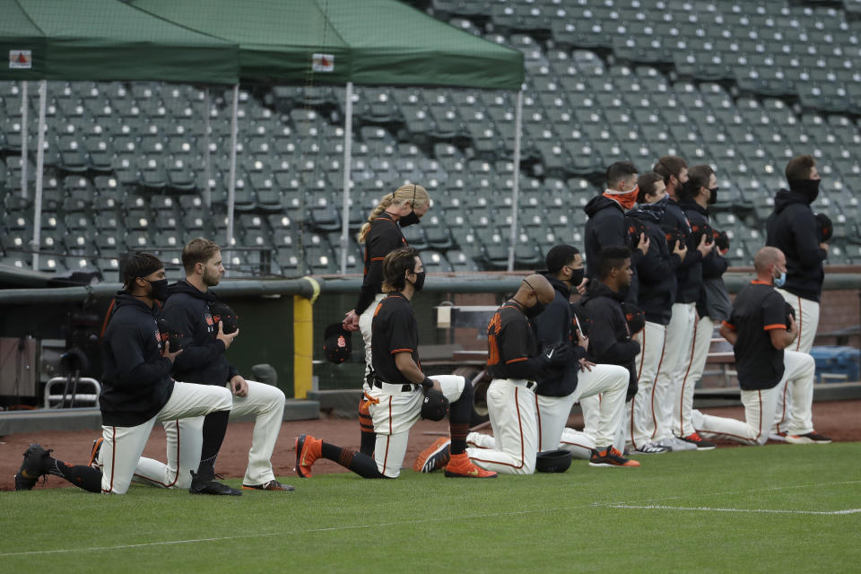 San Francisco Giants players and coaches kneel with others during the national anthem before an exhibition baseball game against the Oakland Athletics in San Francisco, Tuesday, July 21, 2020. (AP Photo/Jeff Chiu)