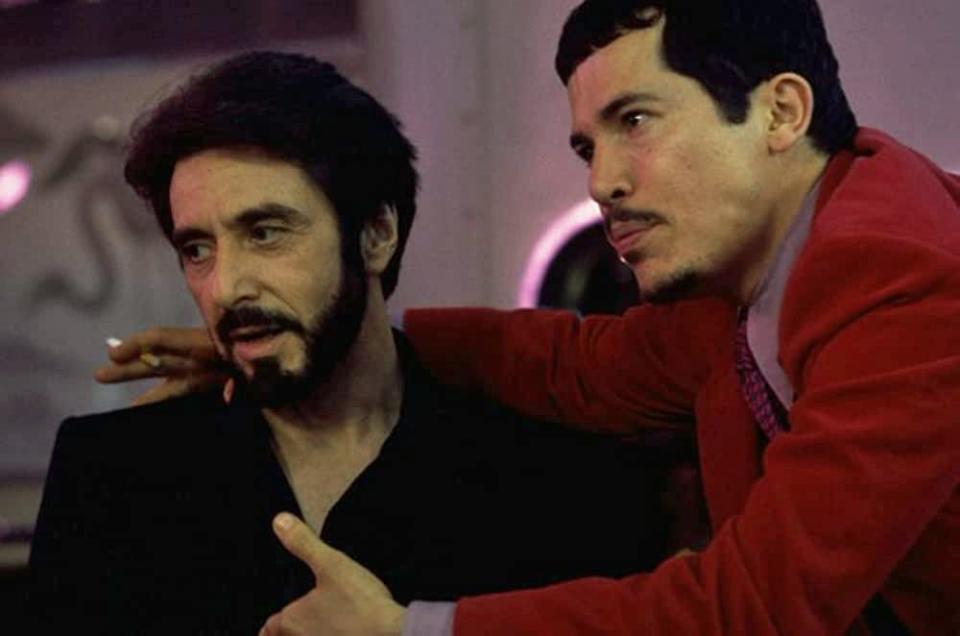 John Leguizamo in a red jacket with his arm around Al Pacino in a black jacket