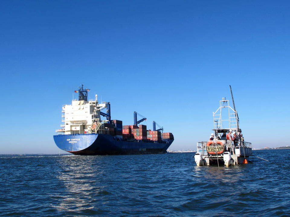 A container ship moves into the harbor in Charleston, S.C., on Friday, Nov. 9, 2012, passing a boat taking sediment samples of the harbor floor. The samples are required for a study of a $300 million deepening of the harbor shipping channel so it can handle larger container ships. (AP Photo/Bruce Smith).