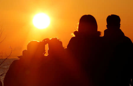 FILE PHOTO: People watch the first sunrise on New Year's Day at a beach in Tokyo, Japan, January 1, 2018. REUTERS/Toru Hanai/File Photo