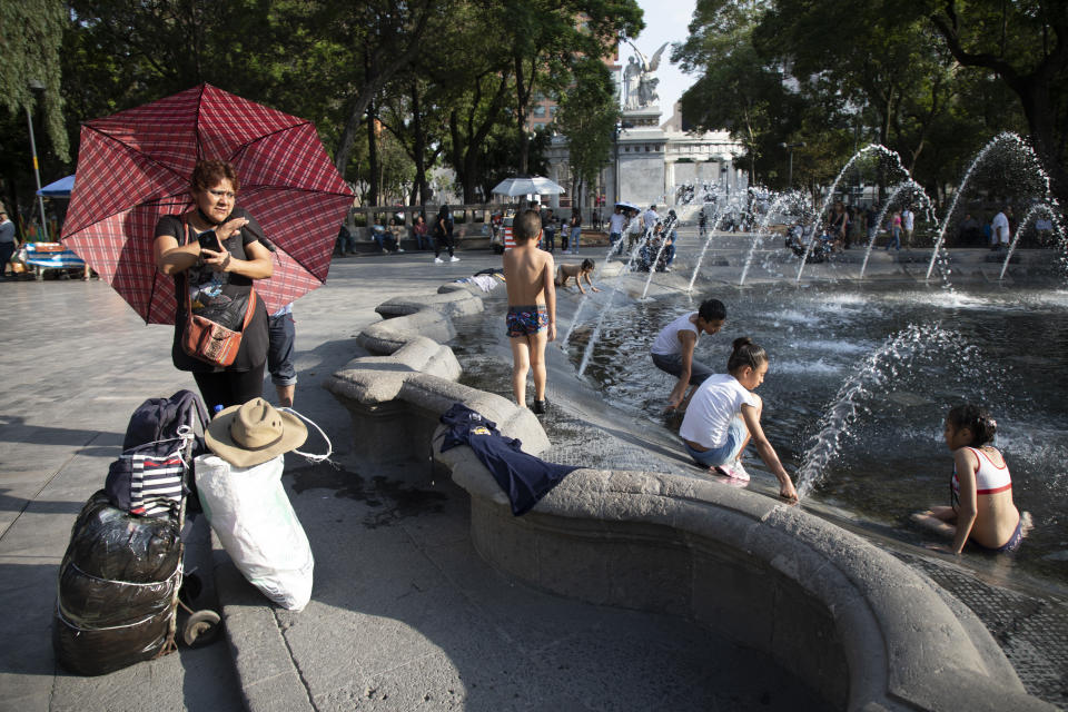 MEXICO CITY, MEXICO - JUNE 16: A woman protects herself from the sun under an umbrella while children and young people cool off in the fountains of the central Alameda in the Historic Center of Mexico City, on June 16, 2023. The third heat wave causes 32°C in Mexico City. The National Meteorological Service forecasts high temperatures that will exceed 35 °C in 30 states of the country. (Photo by Alfredo Martinez/Getty Images)