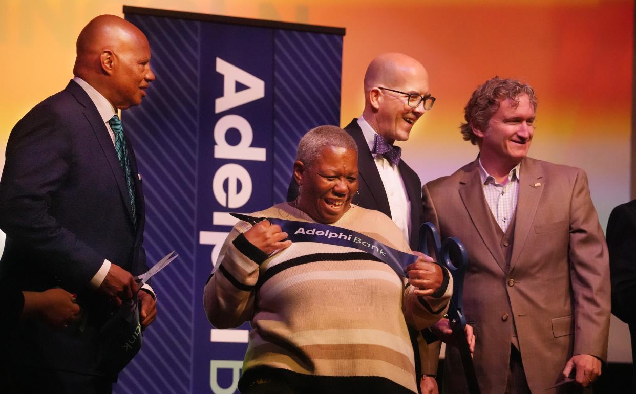 Community member Debera (Momma) Diggs jokes around with the ribbon after cutting it at Adelphi Bank's opening ceremony  Monday afternoon in the Lincoln Theatre. Around her is Adelphi Bank's Chairman and CEO Jordan Miller (from left) and Park National Bank CEO David Trautman and Park CFO Brady Burt.  Hundreds of people took part in a ribbon-cutting ceremony on Monday to celebrate the grand opening of Adelphi Bank, which is currently the only Black-owned bank in Ohio.