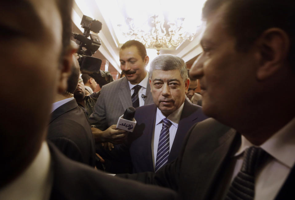 Egypt's Interior Minister Mohammed Ibrahim is surrounded by bodyguards as he leaves a press conference at the interior ministry headquarters in Cairo, Egypt, Monday, May 12, 2014. Egypt's top security official has sought to build claims that the Muslim Brotherhood is backing terrorism, showing alleged confessions of militants saying the received funds from members of the group to attack police and the military. (AP Photo/Amr Nabil)