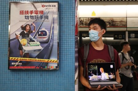 A protester calls people to join further rallies against the government and plays a video of police brutality at Kowloon Tong subway station in Hong Kong