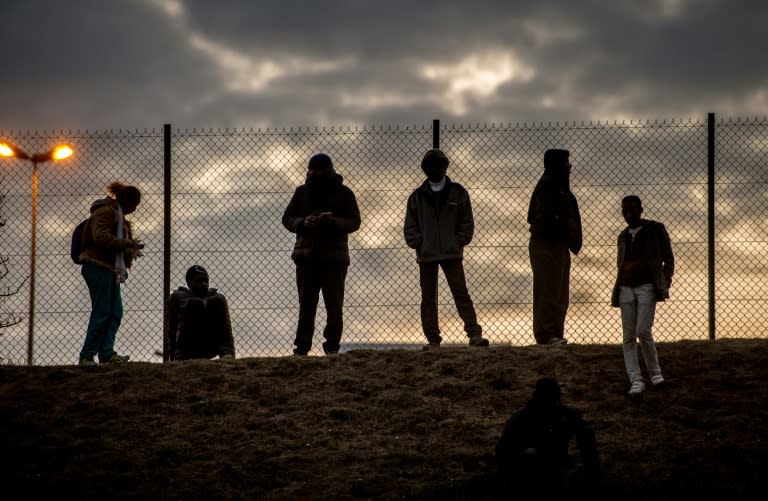 Migrants stand against a chain link fence inside the Eurotunnel site in Coquelles near Calais, northern France on July 30, 2015