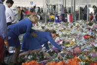 FILE - Two KLM cabin crew reach out into a sea of flowers at Schiphol airport in Amsterdam, on July 22, 2014. A Dutch court on Thursday is set to deliver verdicts in the long-running trial of three Russians and a Ukrainian rebel for their alleged roles in the shooting down of Malaysia Airlines flight MH17 over conflict-torn eastern Ukraine. (AP Photo/Mike Corder, File)