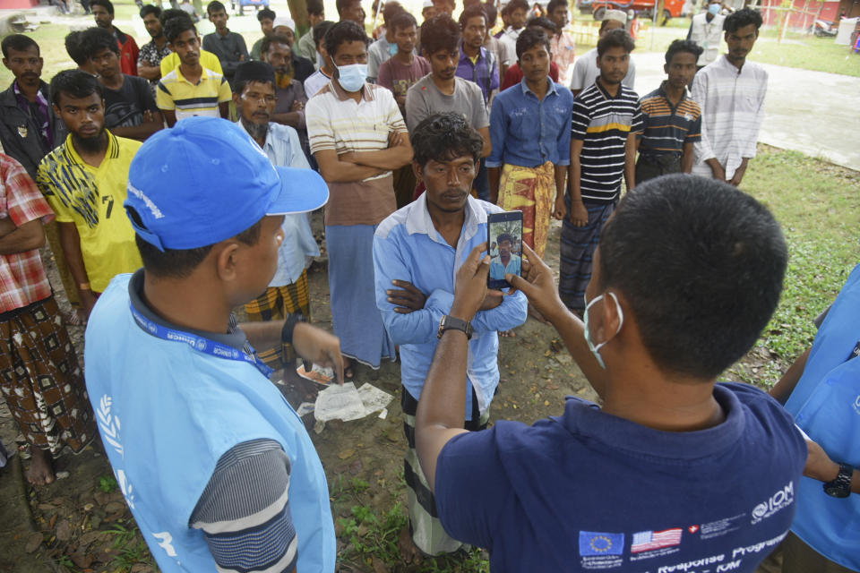 IOM and UNHCR workers take photographs of an ethnic Rohingya man as others wait for their turn to be registered at a temporary shelter in Pidie, Aceh province, Indonesia, Tuesday, Dec. 27, 2022. The United Nations agency is seeking information about the voyage of over 100 Rohingya Muslim refugees who landed on an Indonesian beach this week, and warned Tuesday that there will likely be more. (AP Photo/Rahmat Mirza)