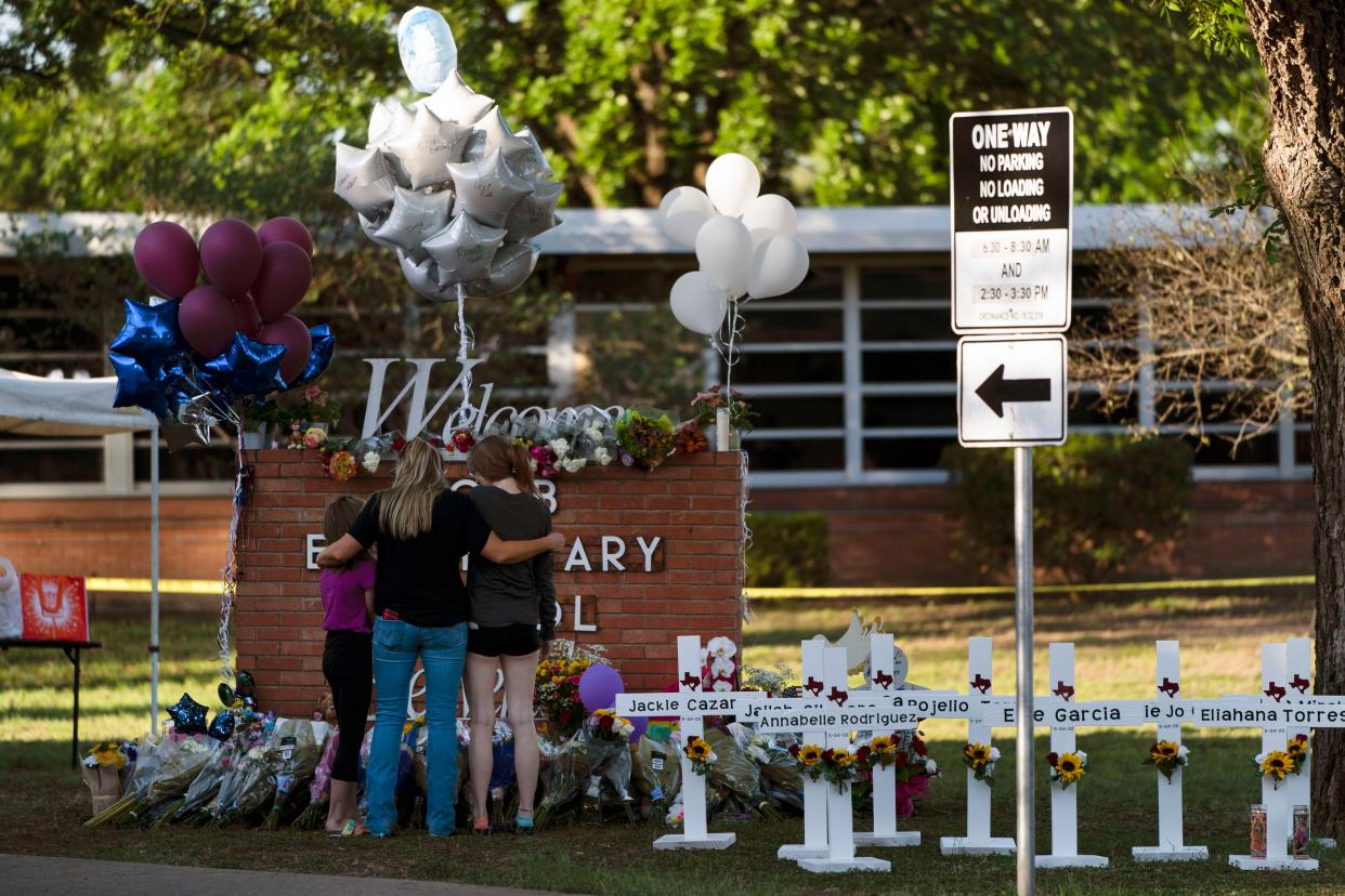 A family pays their respects next to crosses bearing the names of Tuesday's shooting victims at Robb Elementary School in Uvalde, Texas.