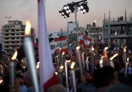 People carry torches during a demonstration marking one year since the start of nation-wide protests near Beirut's port