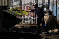 California Governor Gavin Newsom removes cardboard from a Union Pacific railroad site on Thursday, Jan. 20, 2022, in Los Angeles. Gov. Gavin Newsom on Thursday promised statewide coordination in going after thieves who have been raiding cargo containers aboard trains nearing downtown Los Angeles for months, leaving the tracks blanketed with discarded boxes. (AP Photo/Ashley Landis)