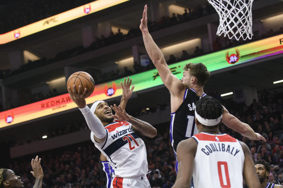 Washington Wizards center Daniel Gafford (21) drives to the basket as Sacramento Kings forward Domantas Sabonis, top right, defends during the first quarter of an NBA basketball game in Sacramento, Calif., Monday, Dec. 18, 2023. (AP Photo/Randall Benton)