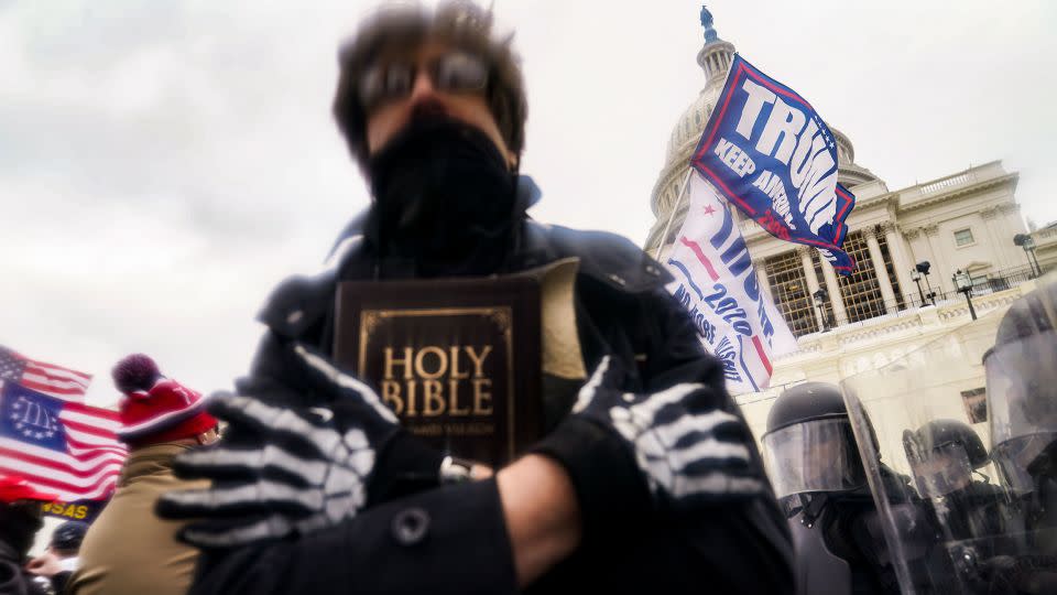 The spread of White Christian nationalism was on display during the January 6 insurrection, which featured many White Christians, like the one above, carrying Bibles and crosses as they rallied in support of former President Trump. - John Minchillo/AP