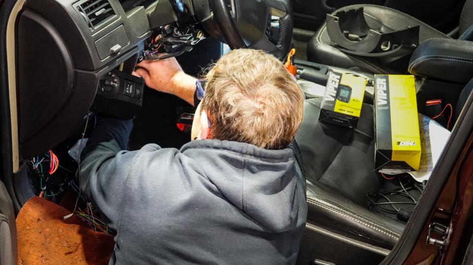 A technician installs an auto immobilizer in a vehicle. Industry reps say anti-theft tech can only prevent theft, and stronger enforcement efforts are needed to address Ontario's car theft crisis. (Stu Mills/CBC - image credit)
