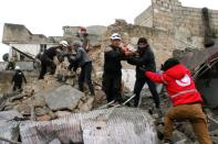 Syrian Civil Defence volunteers rescue children from a damaged building following a reported airstrike that targeted the Idlib bus station on January 18, 2017