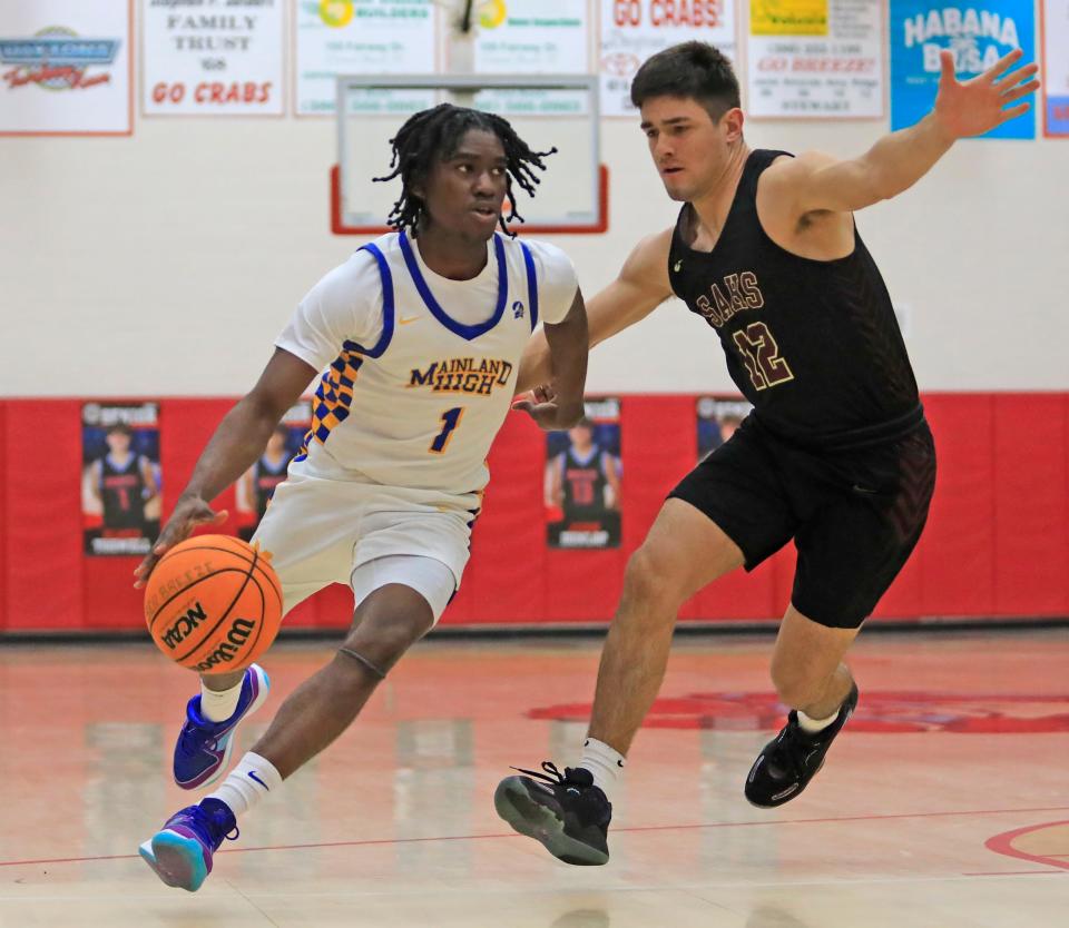 Mainland's Nathan Kirk (1) dribbles past St. Augustine's Julian Quintero (12) during the District 4-5A finals at Seabreeze High School on Saturday, Feb. 10, 2024.