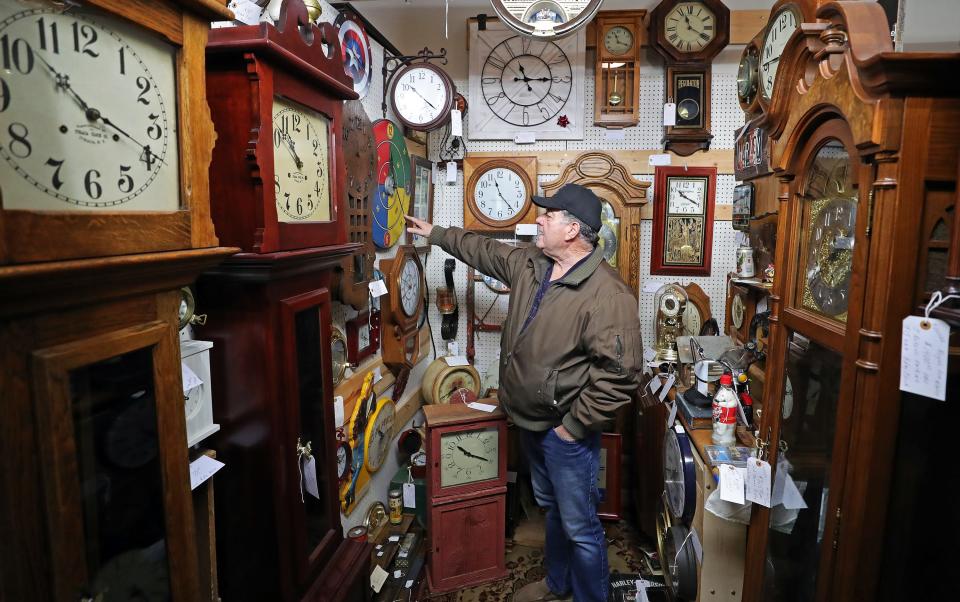 Gail Cousino shows off his collection of antique clocks in his booth at Copley Circle Antiques.