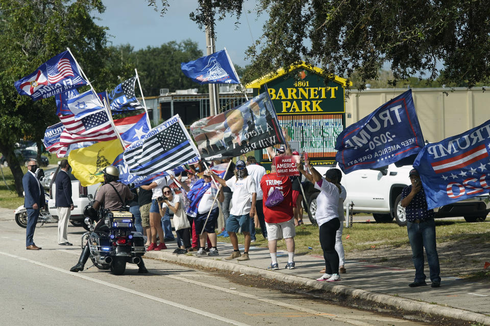 A group of President Donald Trump supporters wave flags along the street as Democratic vice presidential candidate Sen. Kamala Harris, D-Calif., arrives at a campaign eventMonday, Oct. 19, 2020, in Orlando, Fla. (AP Photo/John Raoux)