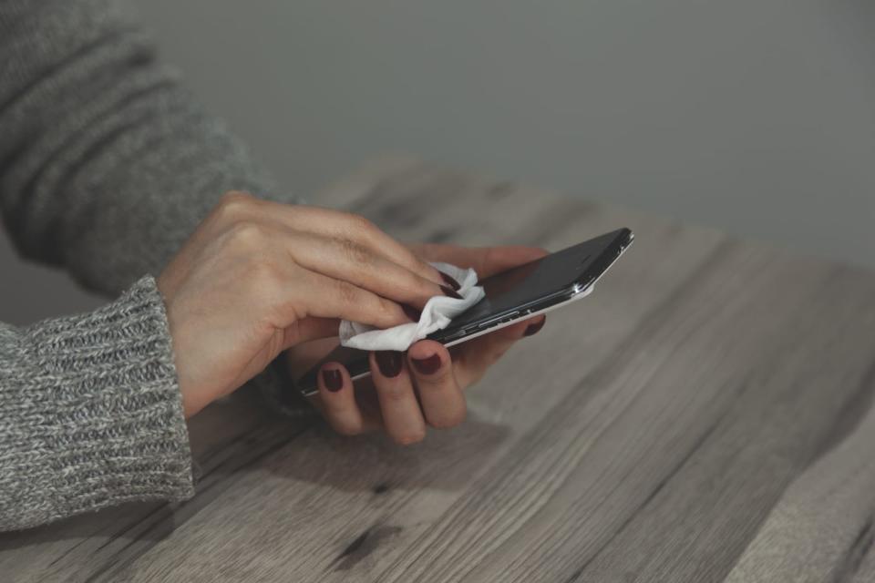 The woman cleans the cell phone with a napkin