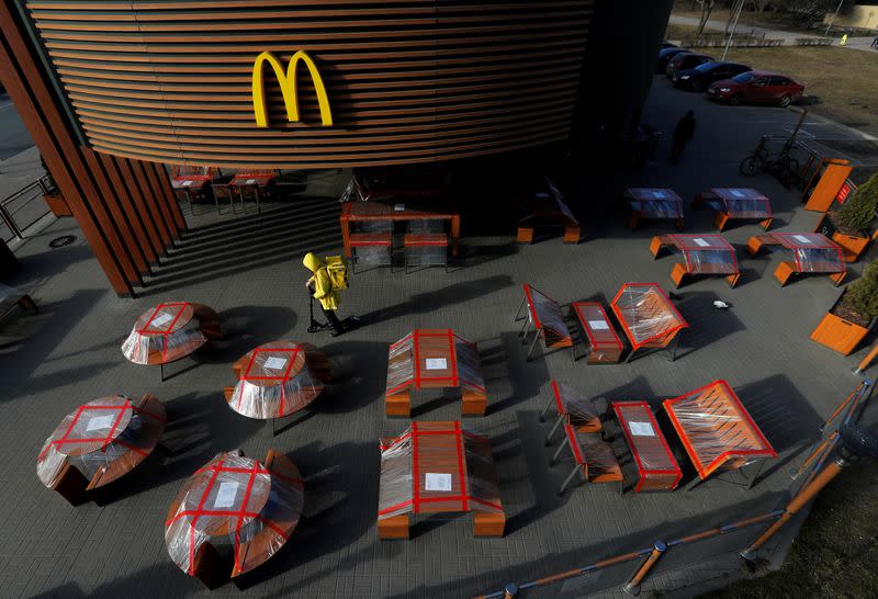 FILE PHOTO: Food delivery courier rides a scooter among plastic-wrapped tables of McDonald's restaurant in Saint Petersburg