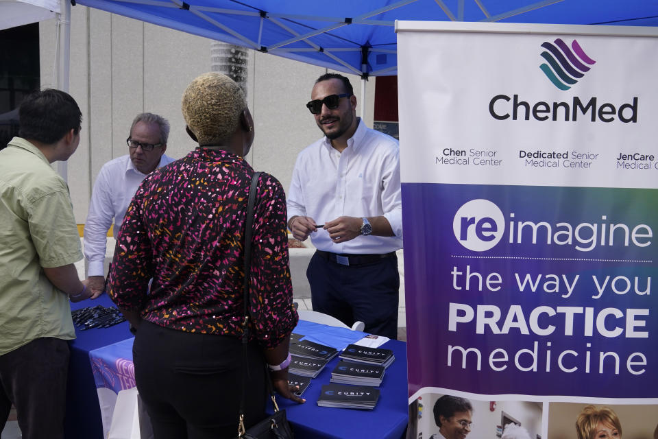 Diego Osorio, center, with ChenMed, talks to a job seeker at the Venture Miami Tech Hiring Fair Thursday, April 14, 2022, in Miami. America’s employers added 428,000 jobs in April, extending a streak of solid hiring that has defied punishing inflation, chronic supply shortages, the Russian war against Ukraine and much higher borrowing costs. (AP Photo/Marta Lavandier)