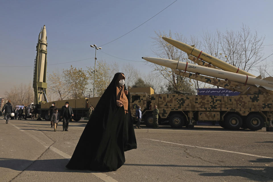 ADDS NAMES OF MISSILES - A woman walks past Qiam, left, Zolfaghar, top right, and Dezful missiles displayed in a missile capabilities exhibition by the paramilitary Revolutionary Guard a day prior to second anniversary of Iran's missile strike on U.S. bases in Iraq in retaliation for the U.S. drone strike that killed top Iranian general Qassem Soleimani in Baghdad, at Imam Khomeini grand mosque, in Tehran, Iran, Friday, Jan. 7, 2022. Iran put three ballistic missiles on display on Friday, as talks in Vienna aimed at reviving Tehran's nuclear deal with world powers flounder. (AP Photo/Vahid Salemi)