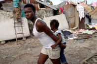 <p>A woman carries a child as they walk in front of destroyed houses after Hurricane Matthew passes Jeremie, Haiti, October 7, 2016. (REUTERS/Carlos Garcia Rawlins)</p>