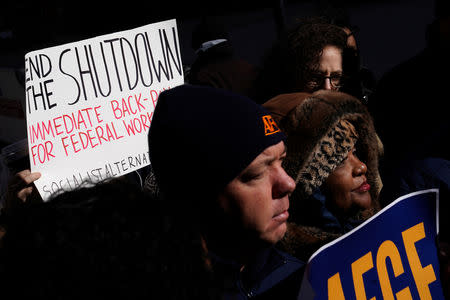 Protestors hold signs during a rally outside a closed federal building in the Manhattan borough of New York City, New York, U.S., January 15, 2019. REUTERS/Carlo Allegri