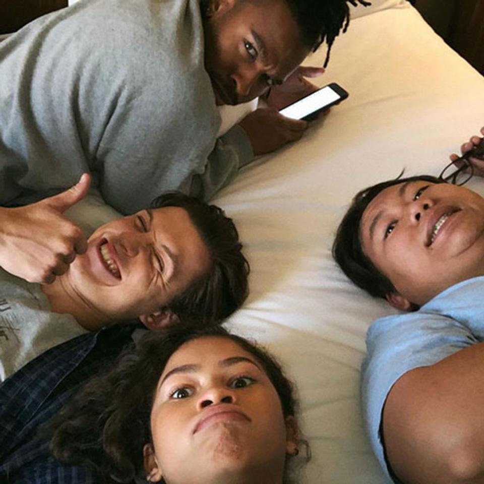The cast of Spider-Man and Darell looking up at the camera while lying on a bed