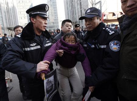 Liu Chunxia, a supporter of Xu Zhiyong, one of China's most prominent rights advocates, is detained by policemen while she gathers with other supporters nearby a court where Xu's trial is being held in Beijing January 22, 2014. REUTERS/Kim Kyung-Hoon