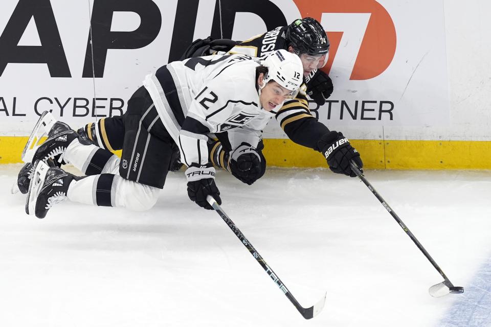 Los Angeles Kings' Trevor Moore (12) and Boston Bruins' Jake DeBrusk (74) battle for the puck during the first period of an NHL hockey game, Saturday, Feb. 17, 2024, in Boston. (AP Photo/Michael Dwyer)