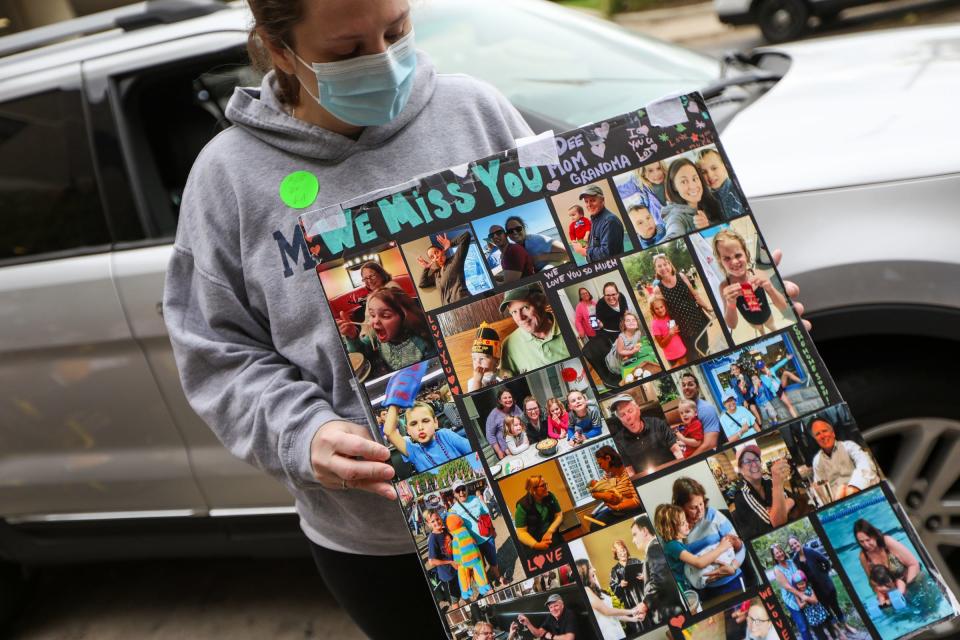 Jennifer Hair, 36, of Canton holds up a poster the family made of pictures of them together to help motivate her mother, Deanna Hair as she battled COVID-19 at the University of Michigan hospital for 196 days.