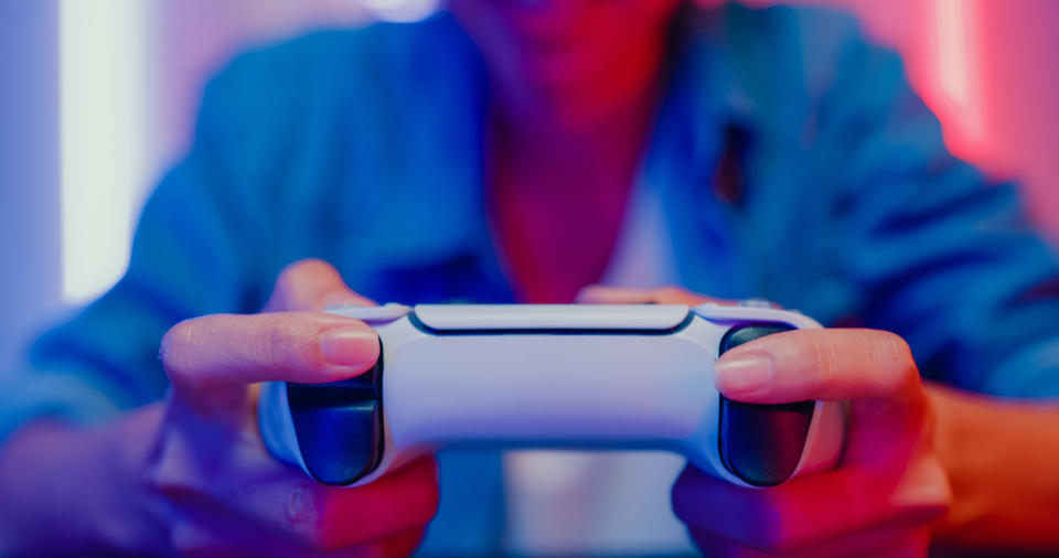 Person holding a game controller, focused on gaming as part of an article on Work & Money in the gaming industry