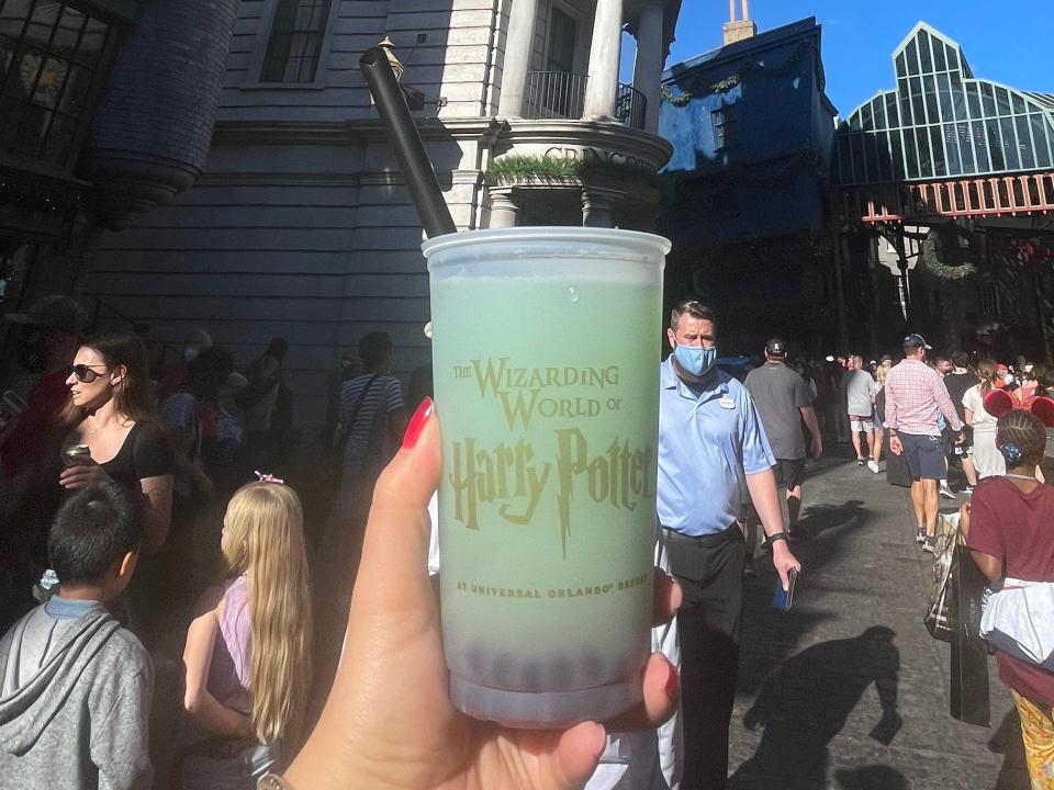 hand holding cup of Fishy green ale from Universal Orlando in wizarding world
