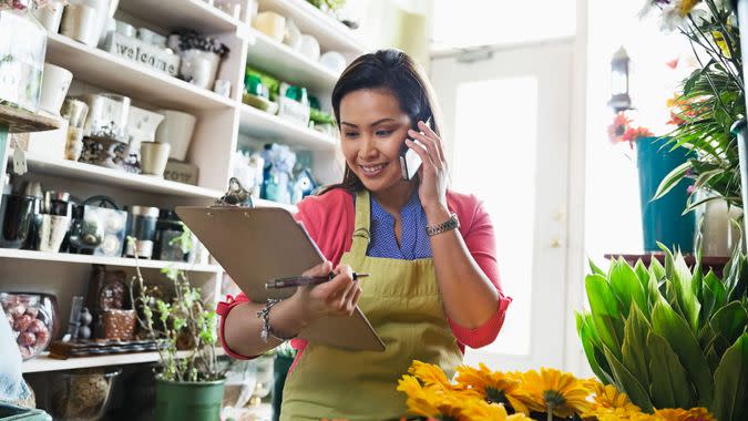 Female florist taking order on mobile phone in flower shop.