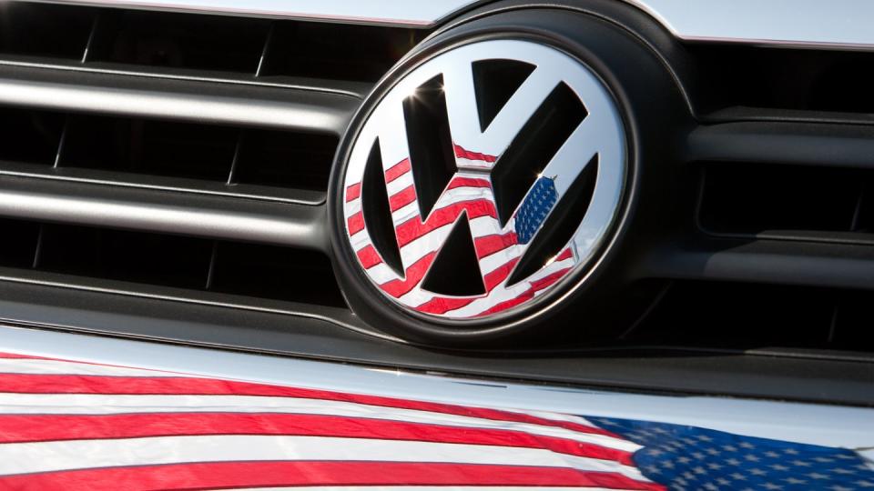 Die US-Fahne spiegelt sich in Logo und Kühlergrill eines VW.