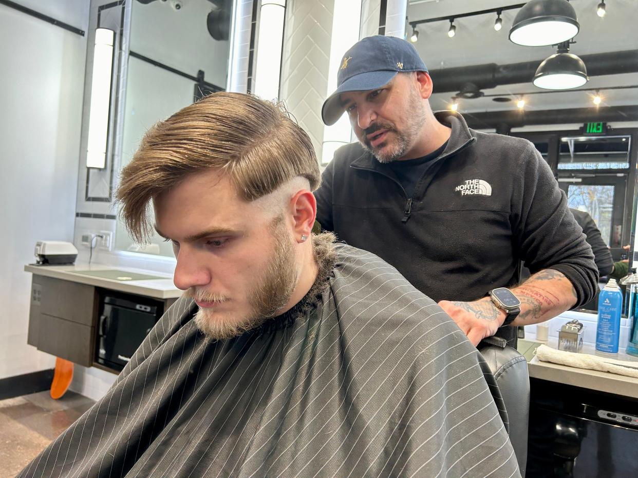 Jason Kraus, 44, of Black Orchid Barbers in the Indianapolis neighborhood of SoBro begins cutting the hair of Zach Dowell, 26, of Franklin.