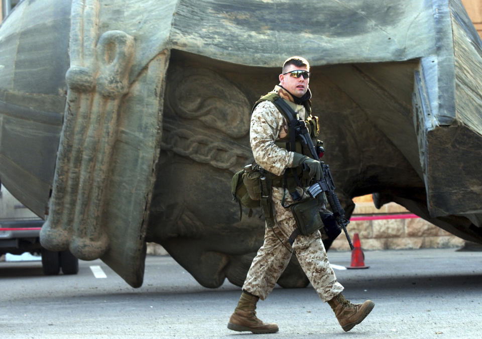 File - A U.S. soldier passes by a huge bust of the ousted Iraqi leader Saddam Hussein outside the al-Salam palace in Baghdad, on Thursday Dec. 11, 2003. Four busts of the former president were taken down from the palace roof recently. (AP Photo/Dusan Vranic, File)