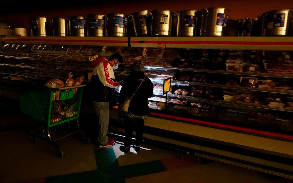 Customers use the light from a cellphone to look in the meat section of a Dallas grocery store on Feb. 16. Though the store lost power, it was open for cash-only sales. (Photo: LM Otero/AP)