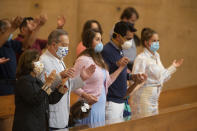 Family members hold hands as they pray at the first English Mass with faithful present at the Cathedral of Our Lady of the Angels in downtown Los Angeles, Sunday, June 7, 2020. Catholic parishes throughout the Archdiocese of Los Angeles suspended public Mass in March amid the coronavirus outbreak. (AP Photo/Damian Dovarganes)