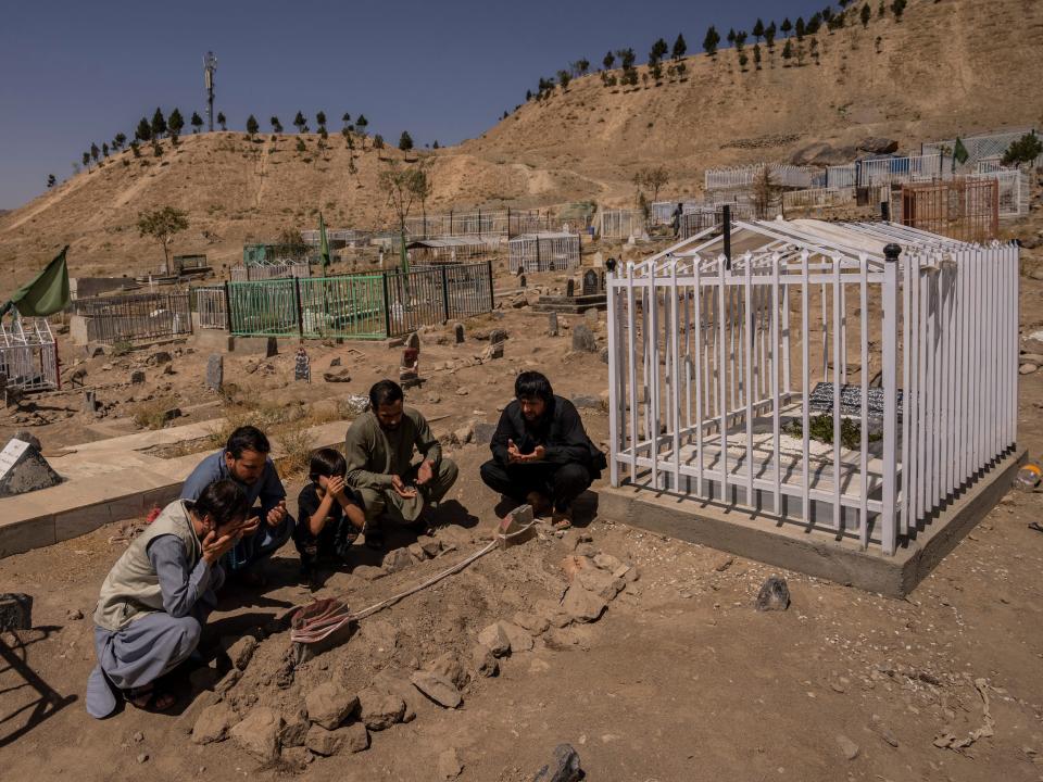 In this Monday, Sept. 13, 2021 file photo, the Ahmadi family pray at the cemetery next to family graves of family members killed by a US drone strike, in Kabul, Afghanistan.