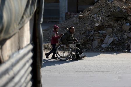 A girl pushes her father on a wheel chair in Douma, Syria February 3, 2016. REUTERS/Bassam Khabieh