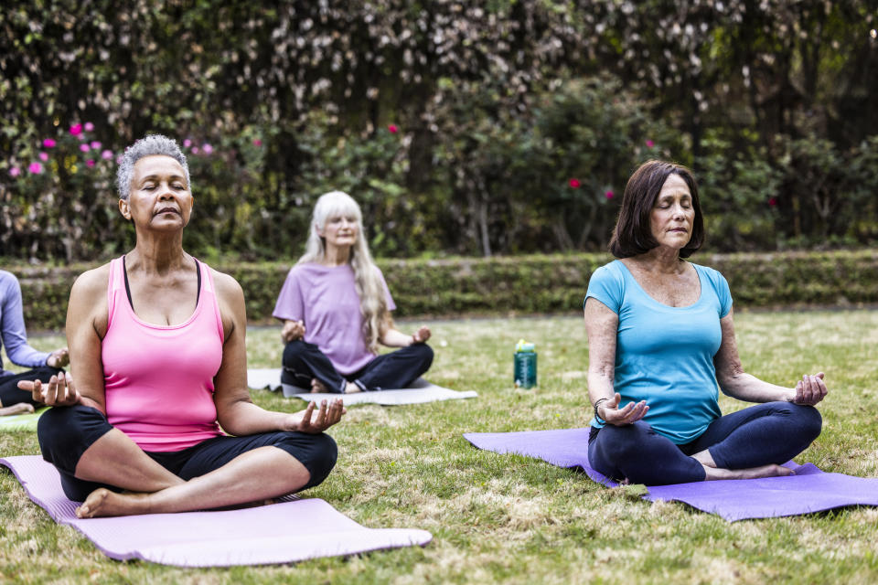 Mujer mayor haciendo clase de yoga al aire libre