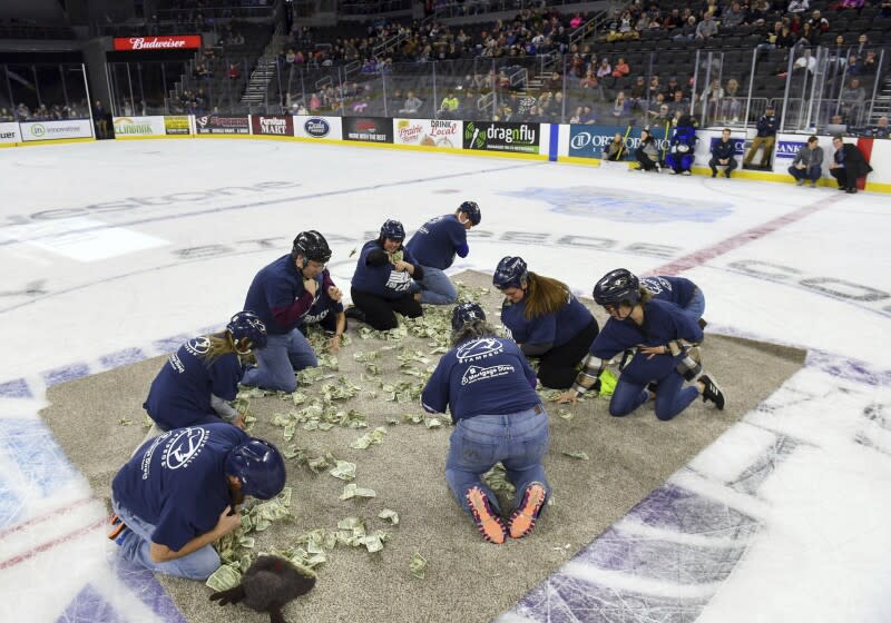 Local teachers scramble for dollar bills to fund projects for their classrooms on Saturday, Dec. 11, 2021, in the first-ever Dash For Cash between periods at the Sioux Falls Stampede game in Sioux Falls, S.D. The organizers of the fundraiser are apologizing after the event was criticized as demeaning. (Erin Woodiel/The Argus Leader via AP)