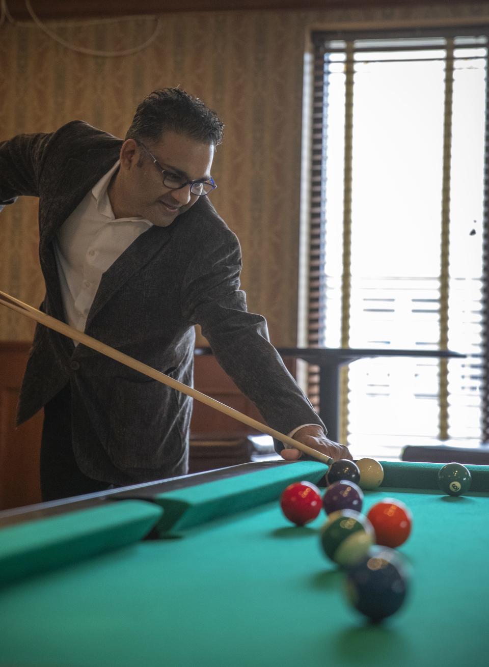 Hotel Mead Resorts & Convention Centers owner Sean Patel aims for the cue ball at one of the new pool tables in the hotel's Grand Avenue Tavern on Tuesday in Wisconsin Rapids.