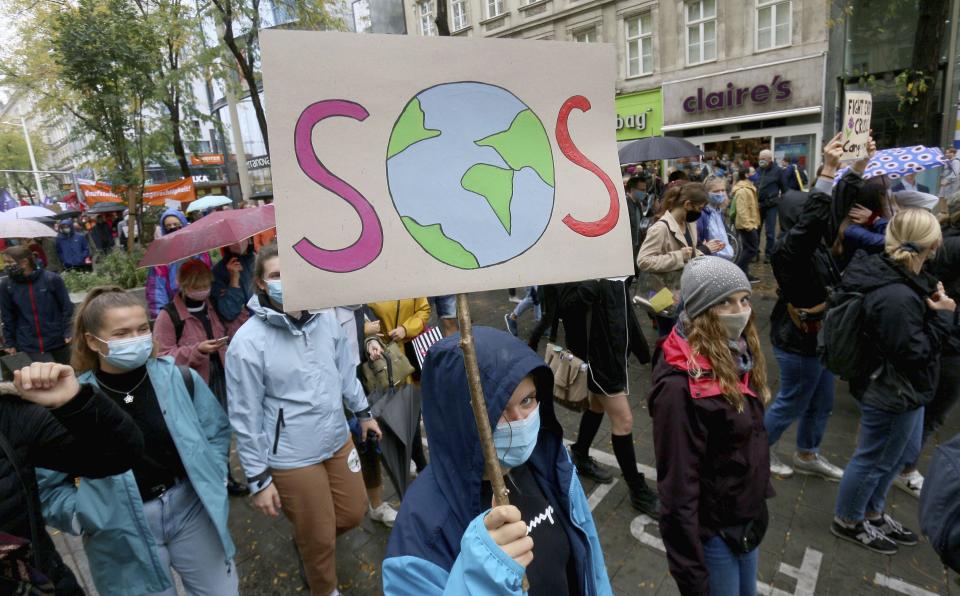 Environmental activists wearing face masks to help protect against the spread of the coronavirus stage during a rally marking the Global Day of Climate Action in Vienna, Austria, Friday, Sept. 25, 2020. (AP Photo/Ronald Zak)