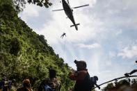 <p>A Thai air force worker drops by helicopter into a clearing in the forest near a possible aboveground opening to the Tham Luang Cave in Chiang Rai Province on June 30, 2018 as the rescue operation continues for the children on a soccer team and their coach. (Photo:Lillian Suwanrumpha/AFP/Getty Images) </p>